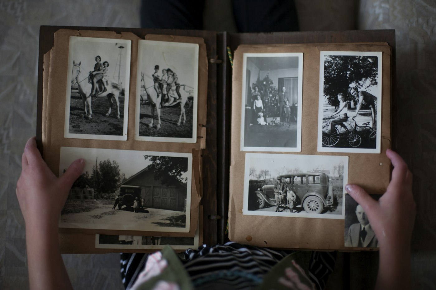 Hands opening a photo album of black-and-white prints